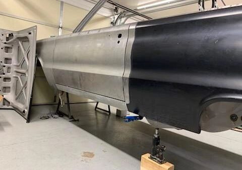 Car body restoration in progress in garage.