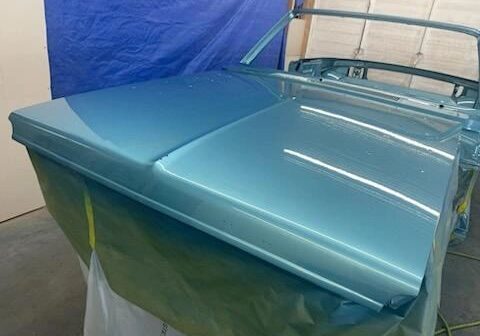 Blue car hood in a workshop setting.