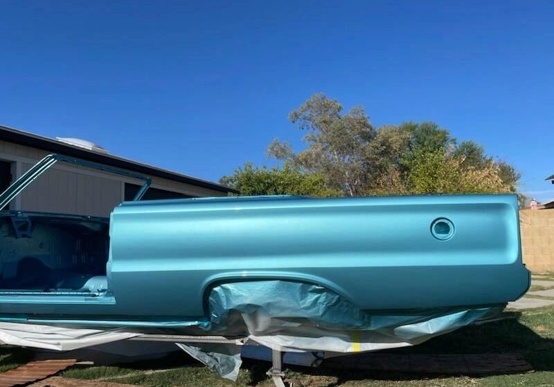 Blue car body under clear blue sky.
