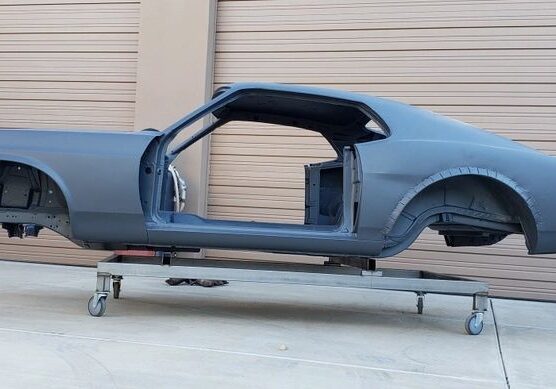 Gray car chassis on wheeled platform.