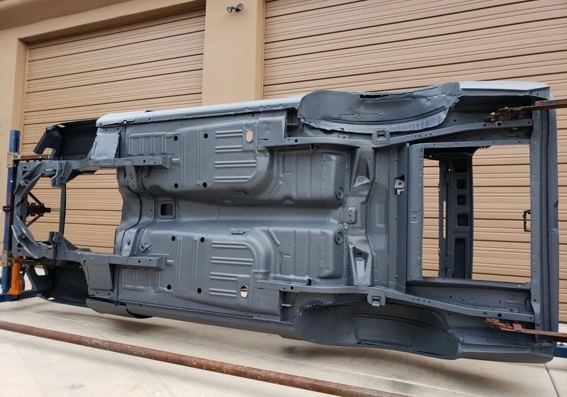 Car chassis on its side outside garage.