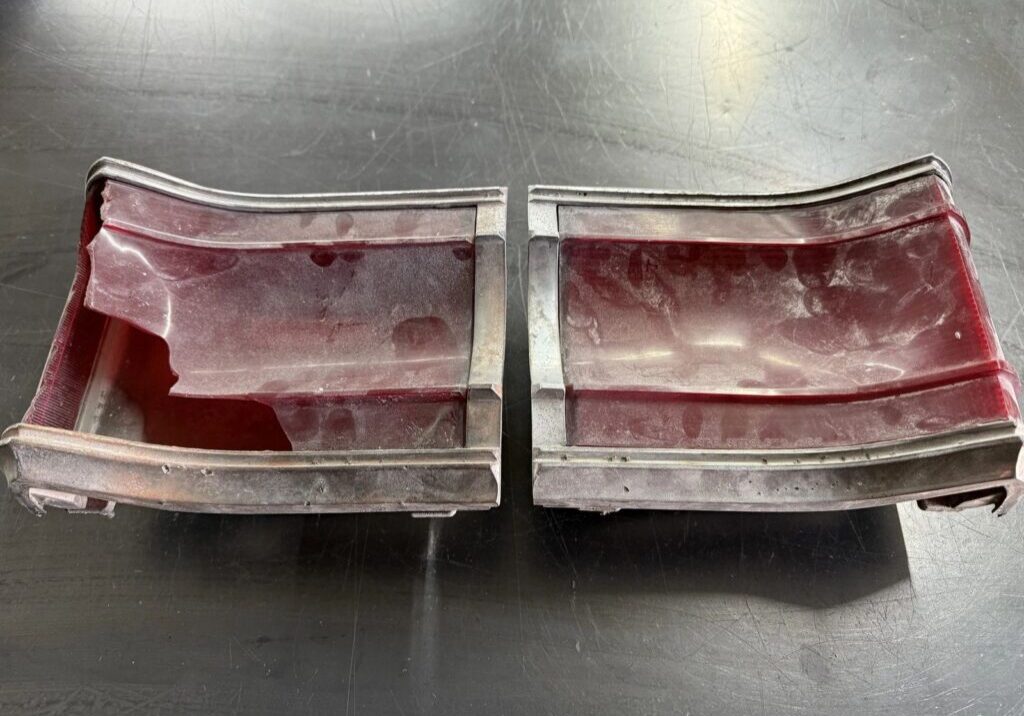 Broken red tail light on black surface.