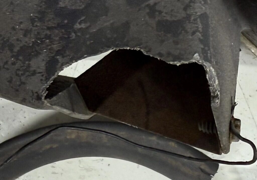 Damaged metal part with exposed interior section.