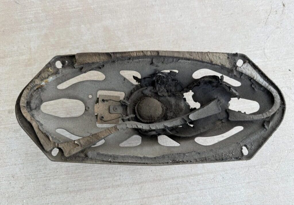 Damaged, burnt speaker on a white surface.
