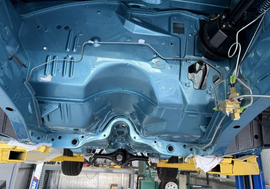 Car chassis on hydraulic lift in garage.